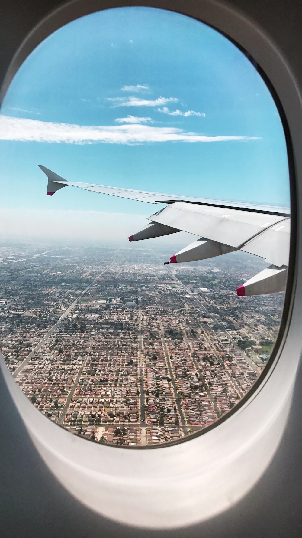 airplane wing over city during daytime