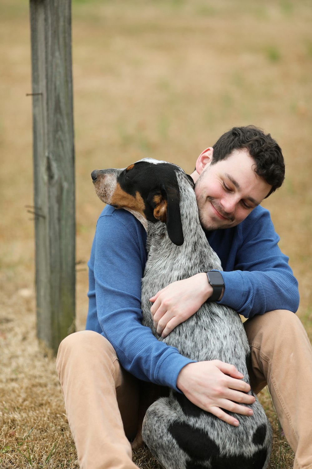 woman in purple jacket holding black and white short coated dog