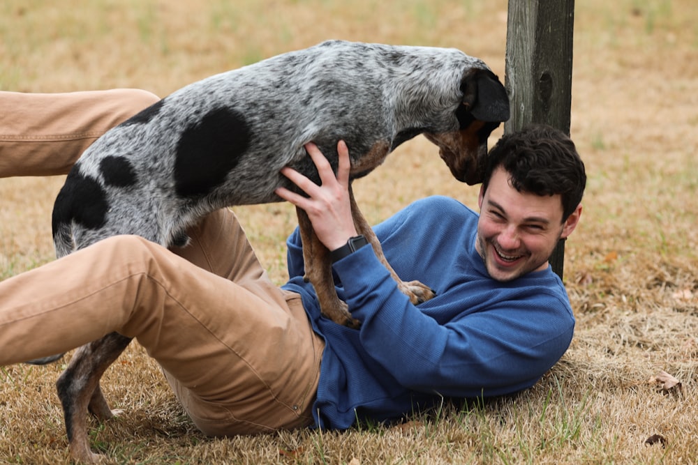 man in black jacket and brown pants holding black and white short coated dog