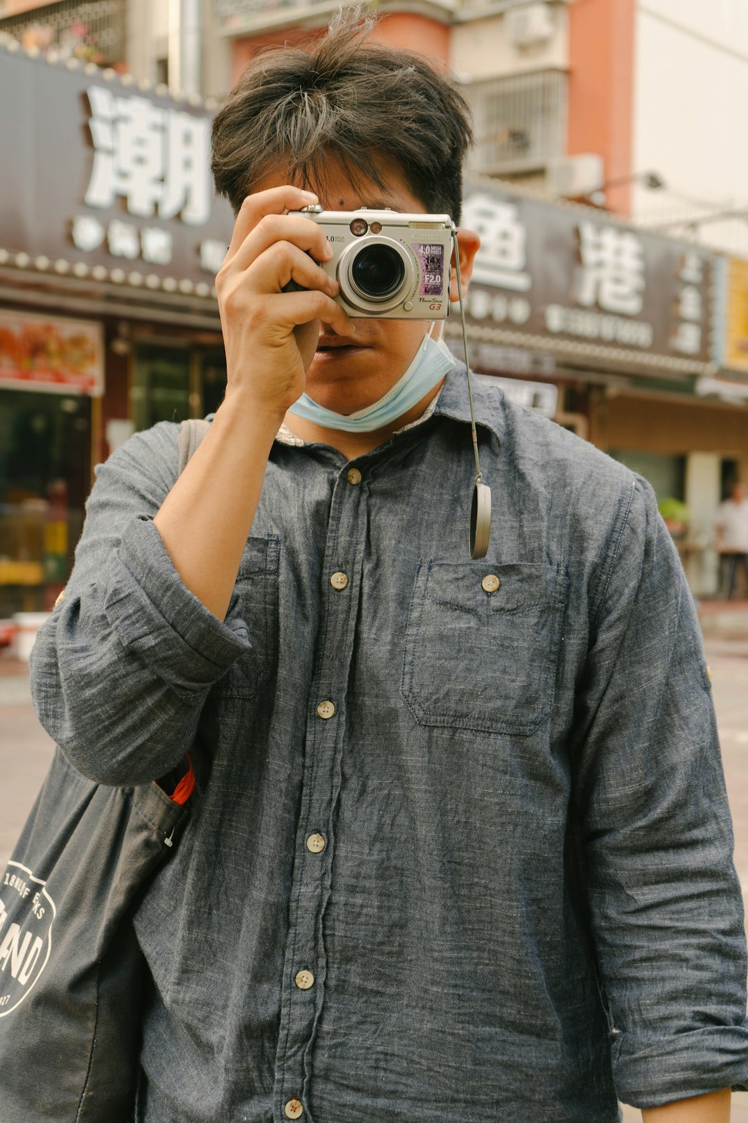 man in gray button up long sleeve shirt holding silver and black camera