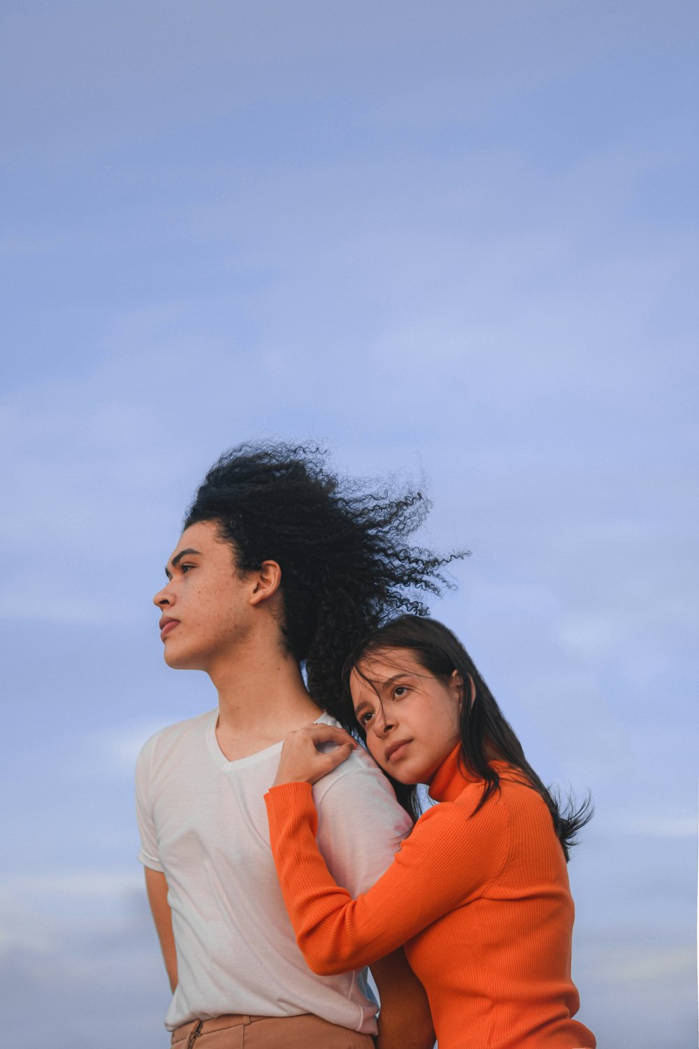 man in white crew neck shirt beside woman in orange shirt