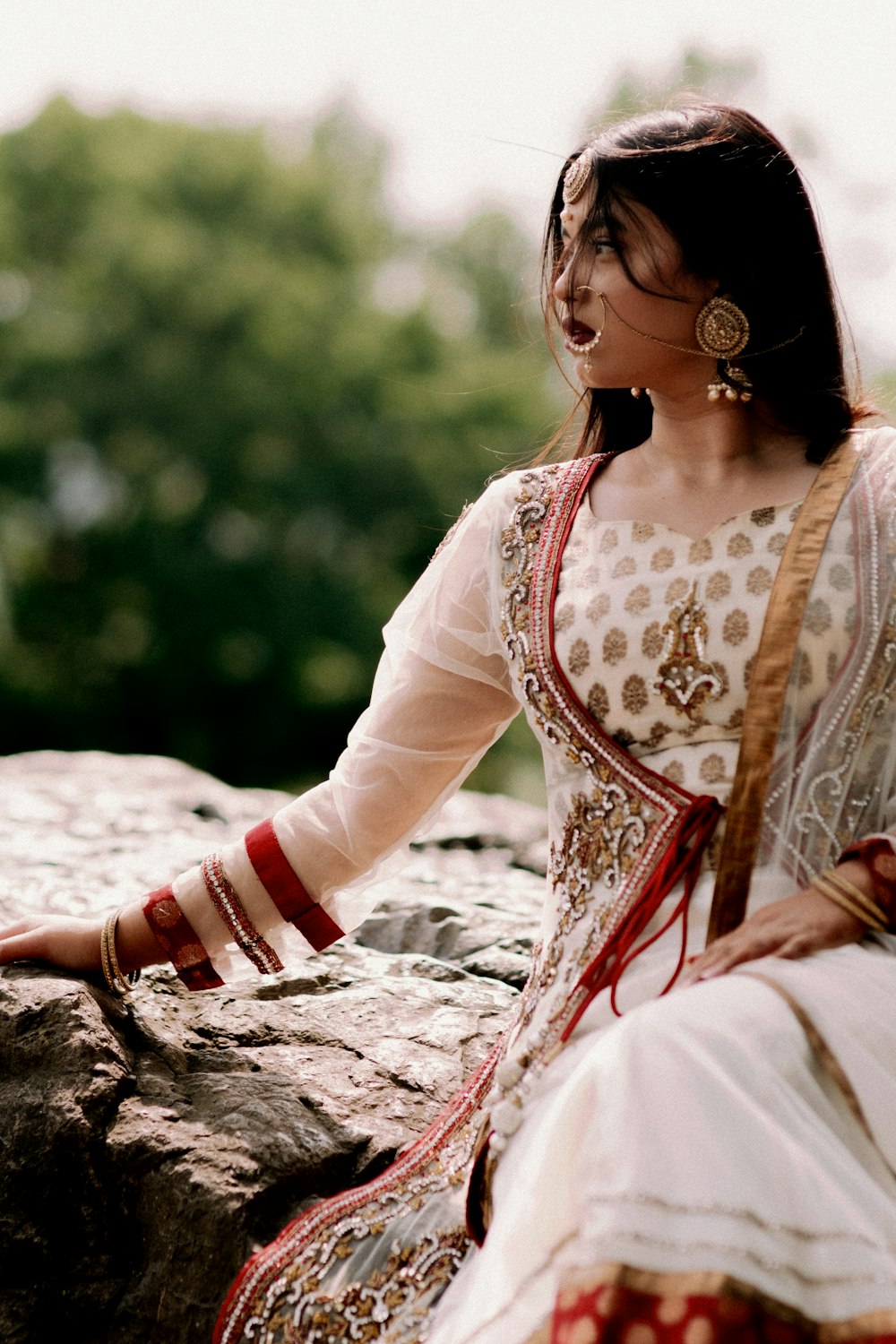 woman in white and red dress sitting on rock during daytime