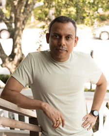 man in white crew neck t-shirt sitting on white wooden bench during daytime