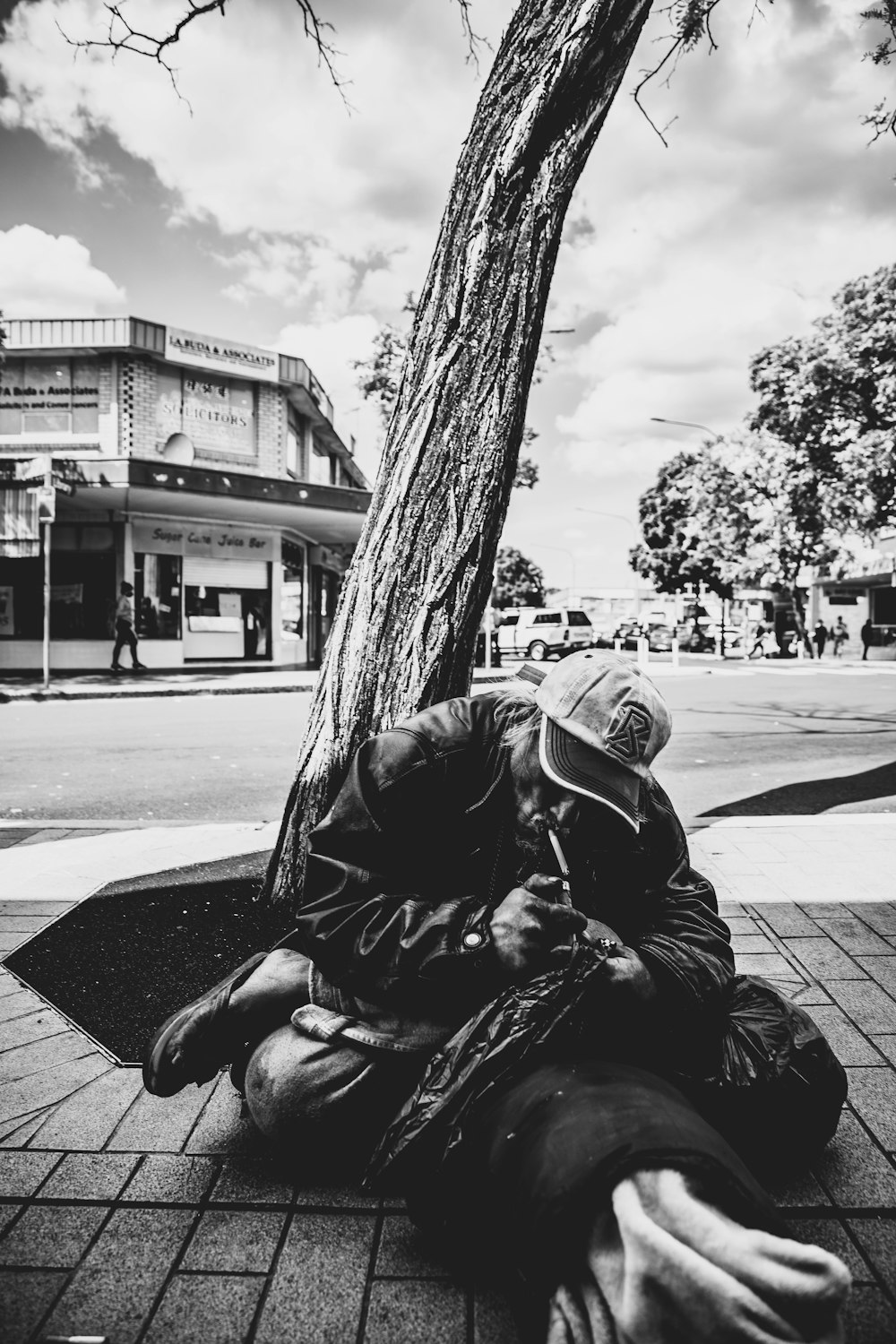 man in black leather jacket sitting on sidewalk during daytime