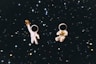 Dva malí astronauti držící zlaté hvězdy ve vesmíru.