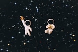 Dva malí astronauti držící zlaté hvězdy ve vesmíru.