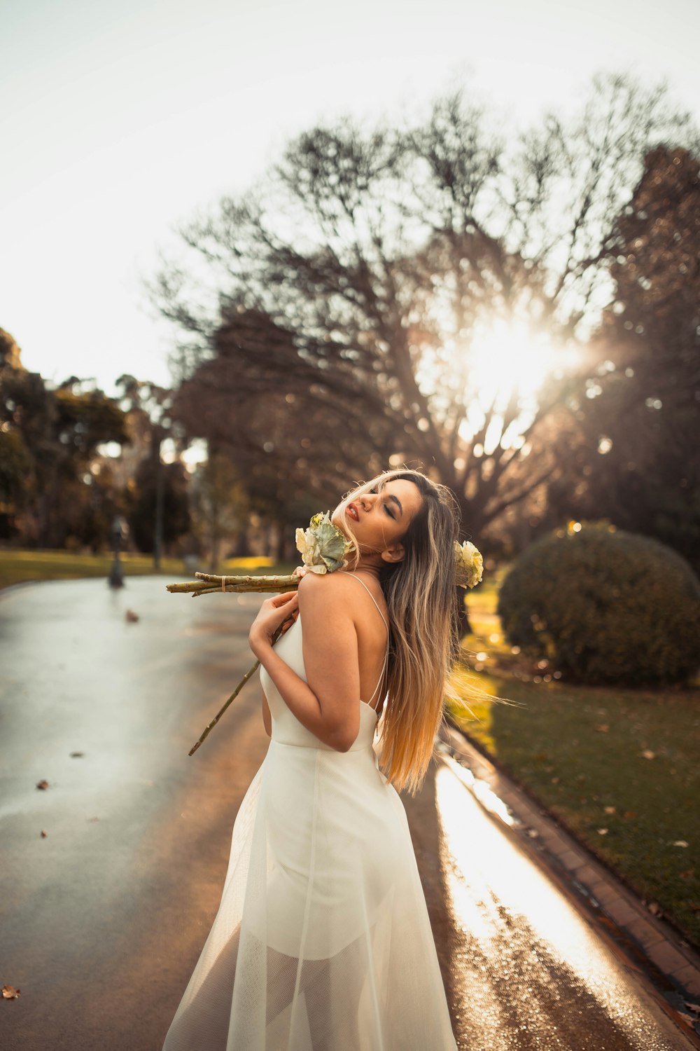 woman in white tank top wearing sunglasses standing on sidewalk during daytime