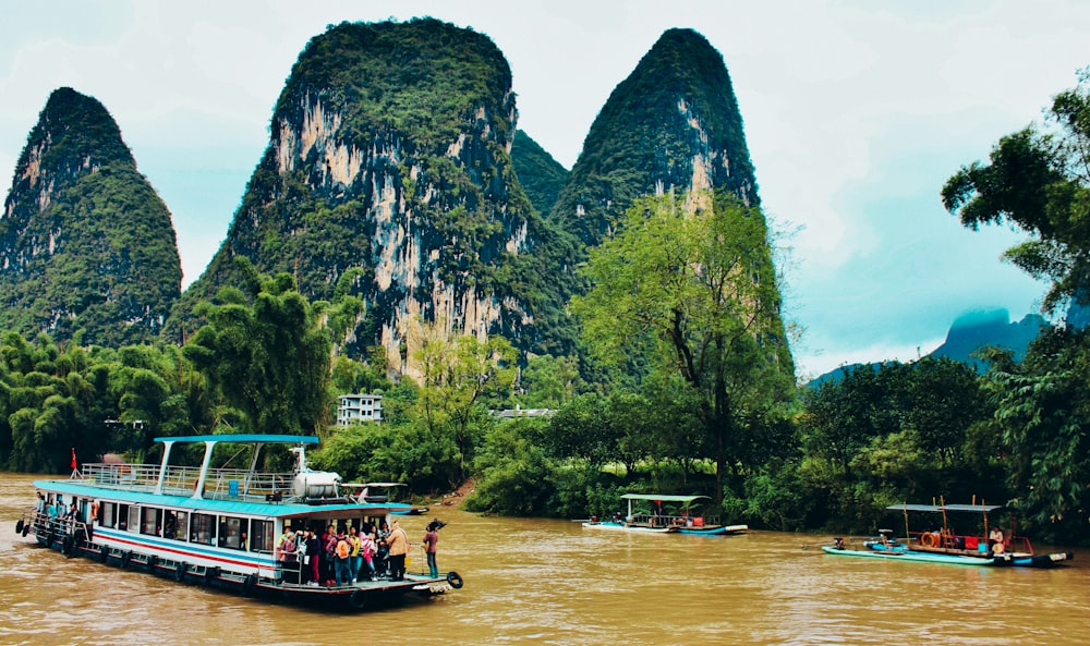 people riding on boat on river near mountain during daytime