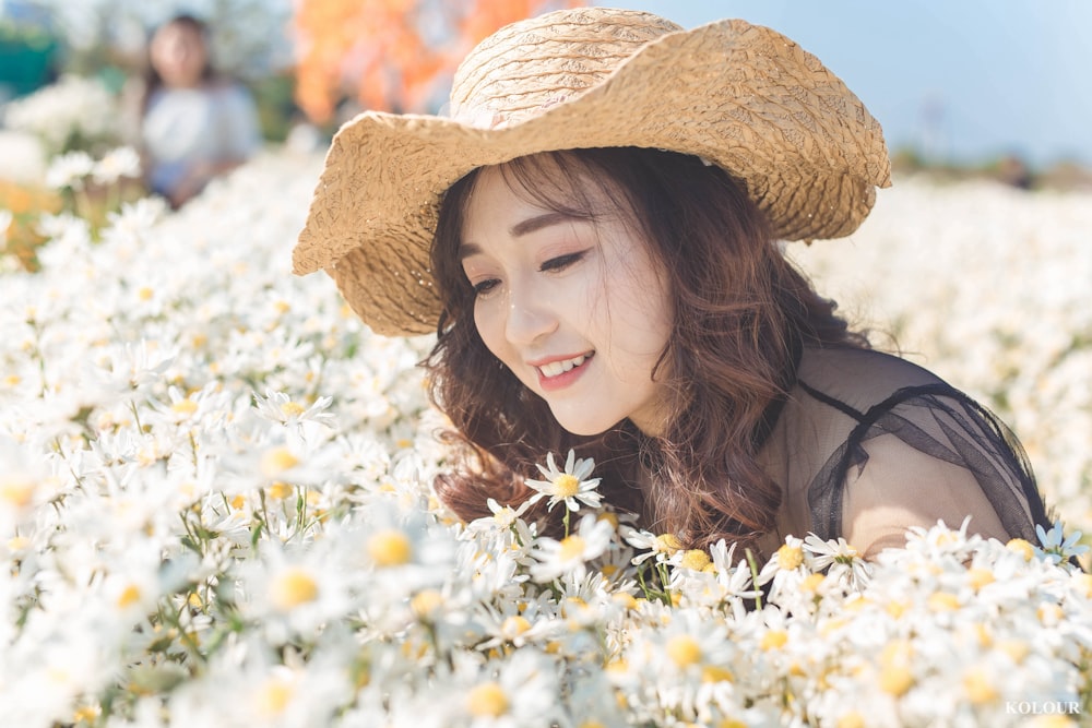 woman in brown sun hat standing beside white flowers during daytime
