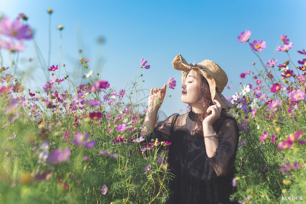 woman in black dress standing on flower field during daytime