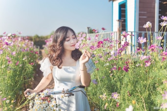 woman in white dress standing on flower field during daytime