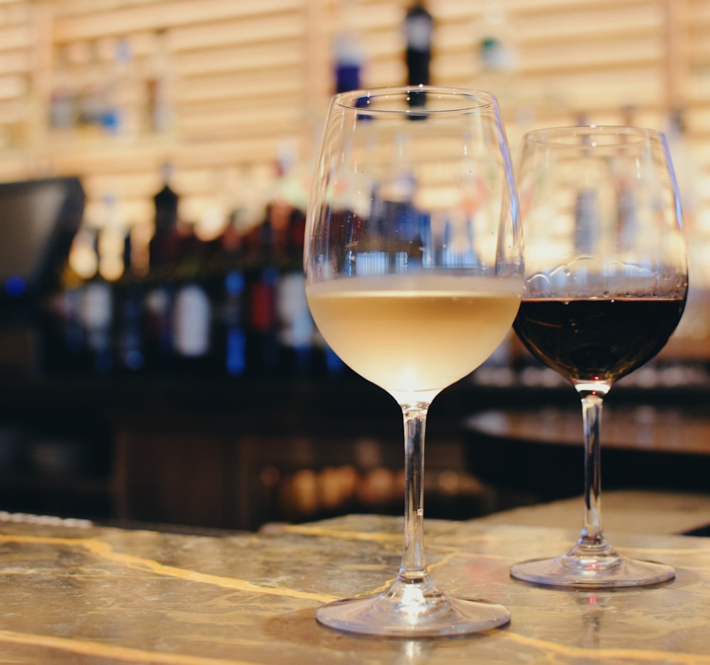 clear wine glass with yellow liquid on brown wooden table