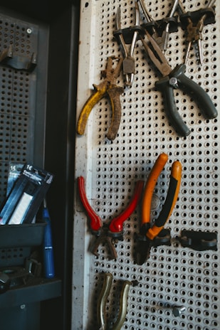 A selection of sturdy hand tools like hammers, screwdrivers, and wrenches hanging on a pegboard.