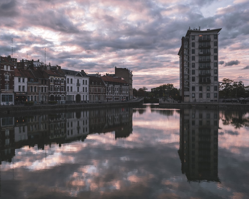 body of water near buildings under cloudy sky during daytime