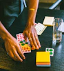 A cheerful artist’s hands arranging colorful stickers and crafts on a rustic wooden table.