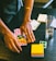 Close-up of a hand applying glue stick on paper in a bright office setting.