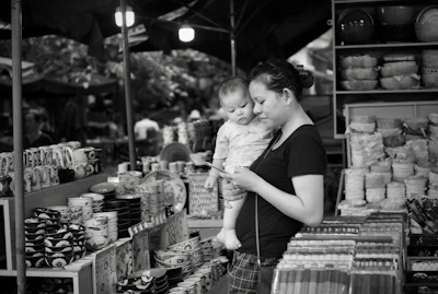A smiling mother feeding her child with Bumi Asih's abon balita in a bright morning market stall