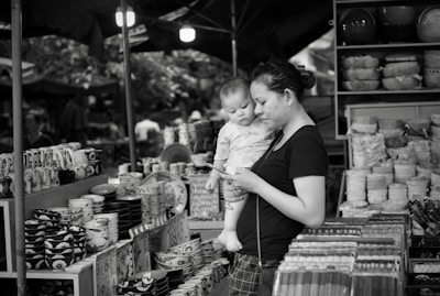 A mother entrepreneur proudly displaying her small business products while caring for her child.