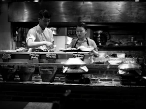 A friendly technician assisting a restaurant chef next to commercial kitchen equipment.