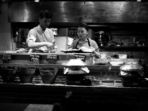 A friendly technician assisting a restaurant chef next to commercial kitchen equipment.