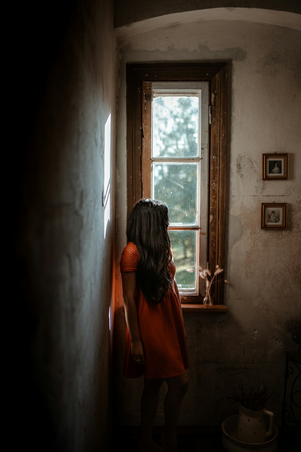 woman in orange dress standing in front of window