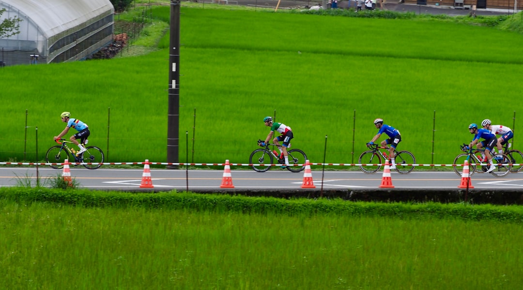2 men riding bicycle on track field during daytime
