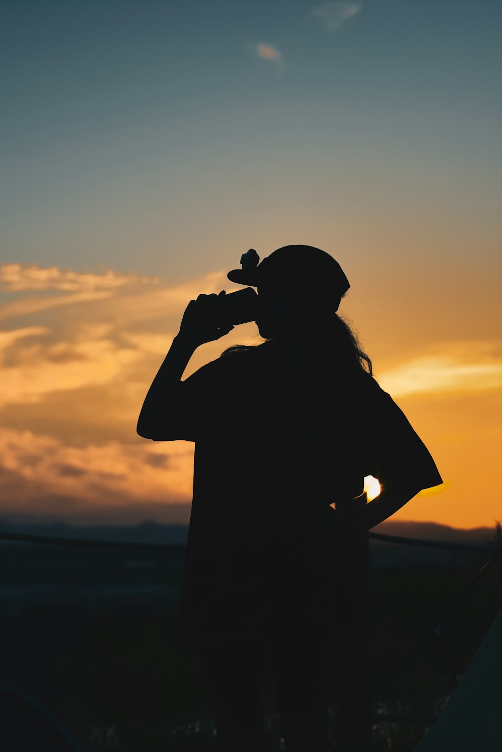Silhouette eines Mannes, der die Kamera während des Sonnenuntergangs hält