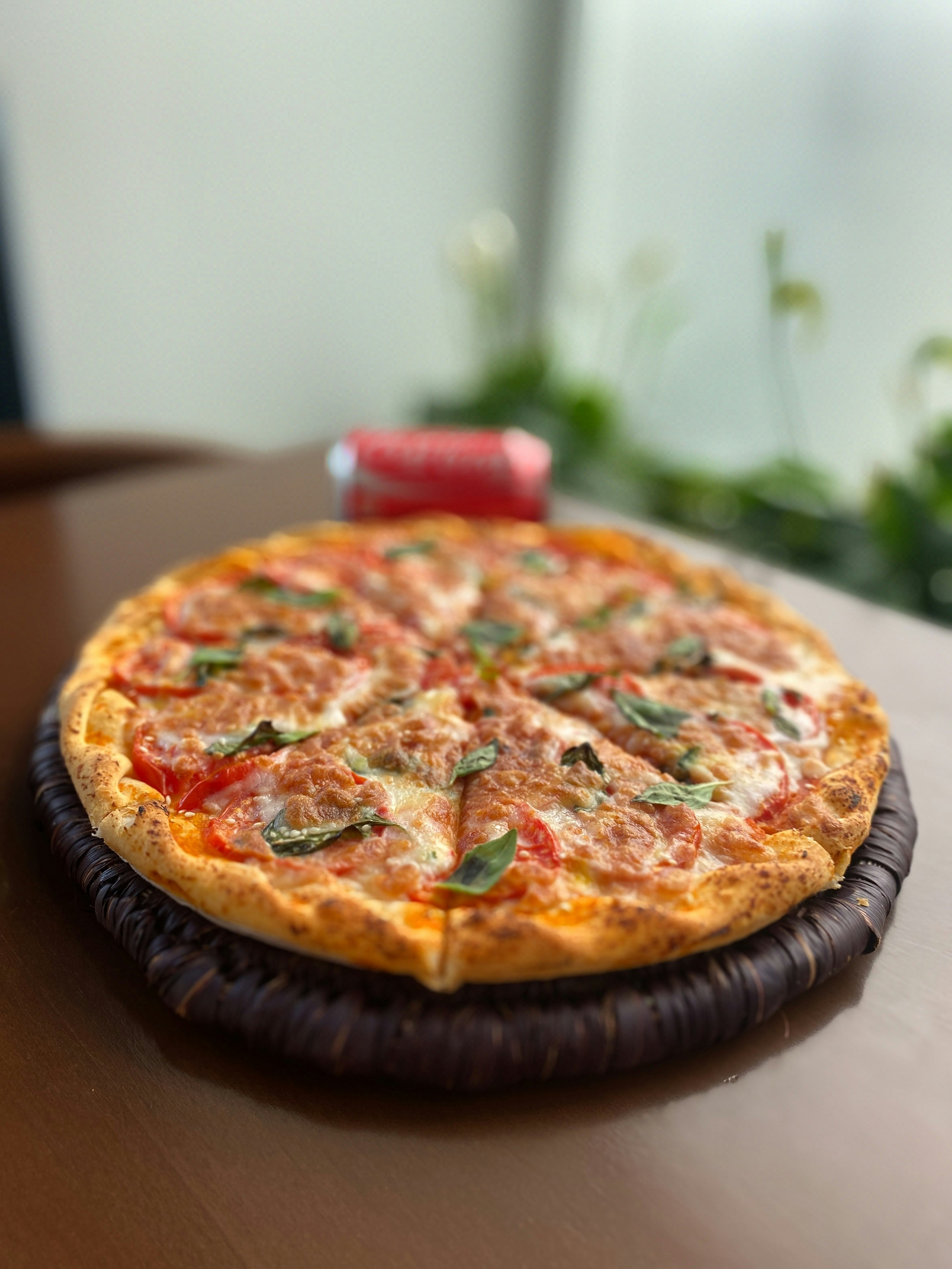 Wood-fired margherita pizza with fresh basil and melted mozzarella on a dark rustic surface