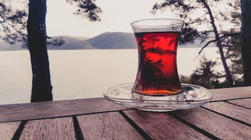 A serene morning scene with a steaming cup of tea on a wooden table.
