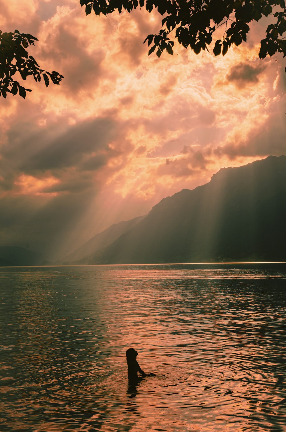 body of water near mountain under cloudy sky during daytime