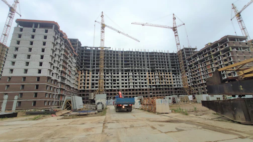 A construction site with cranes and workers overseeing a large industrial warehouse project.