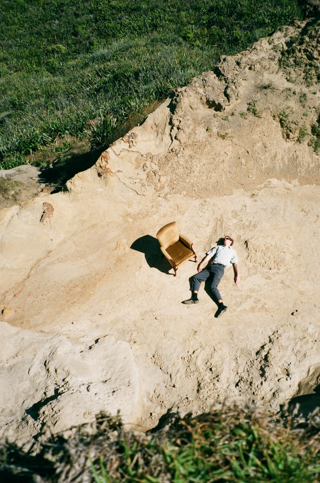 woman in white shirt and black pants sitting on brown rock during daytime