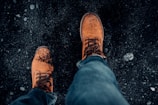 Close-up of sturdy boots standing on freshly tilled soil.