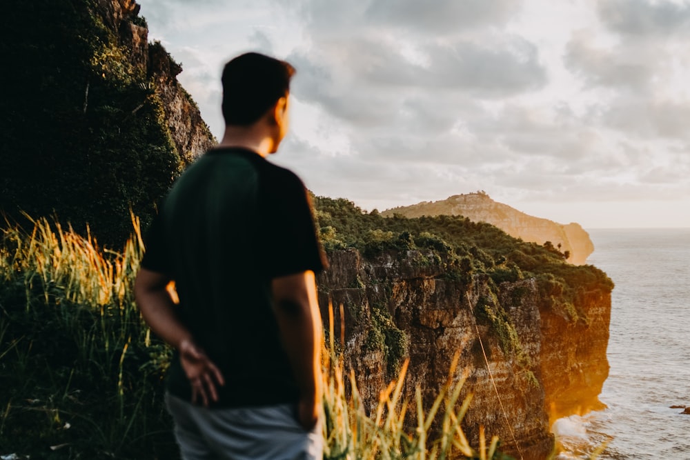 man in black t-shirt and white shorts standing on cliff during daytime