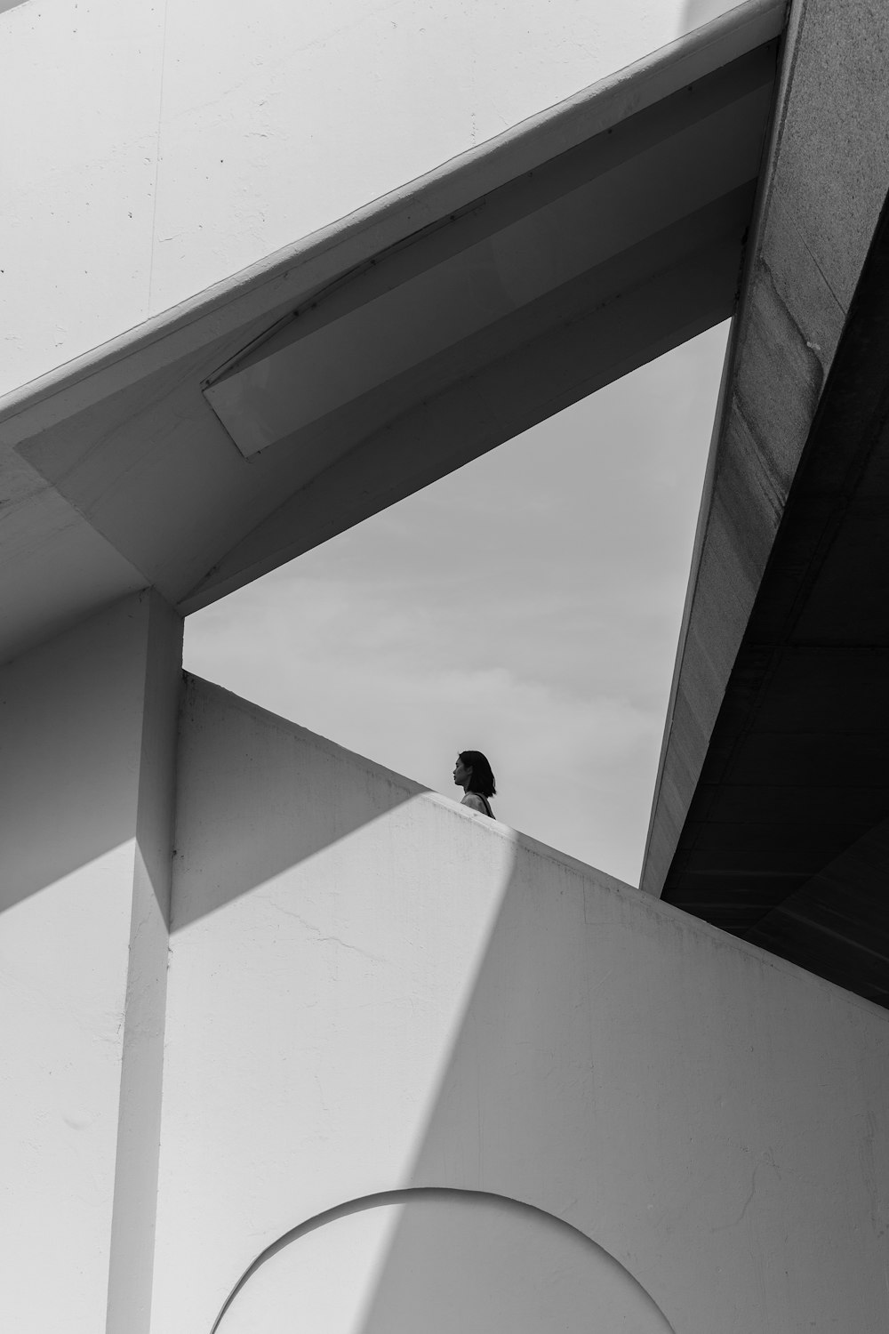 man in black jacket sitting on white concrete wall during daytime