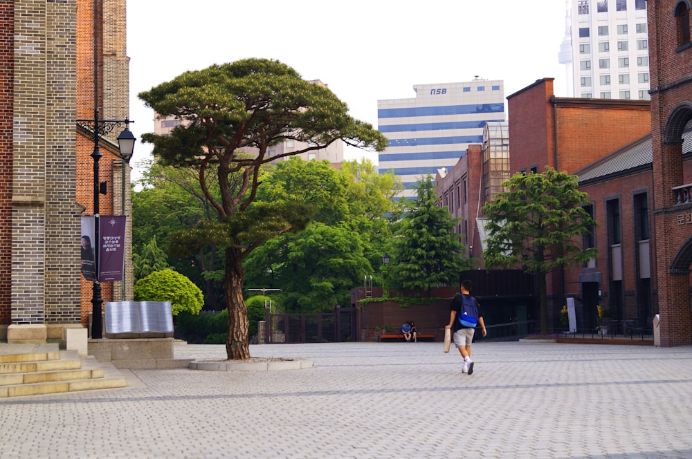 man in black t-shirt and blue denim shorts walking on sidewalk during daytime