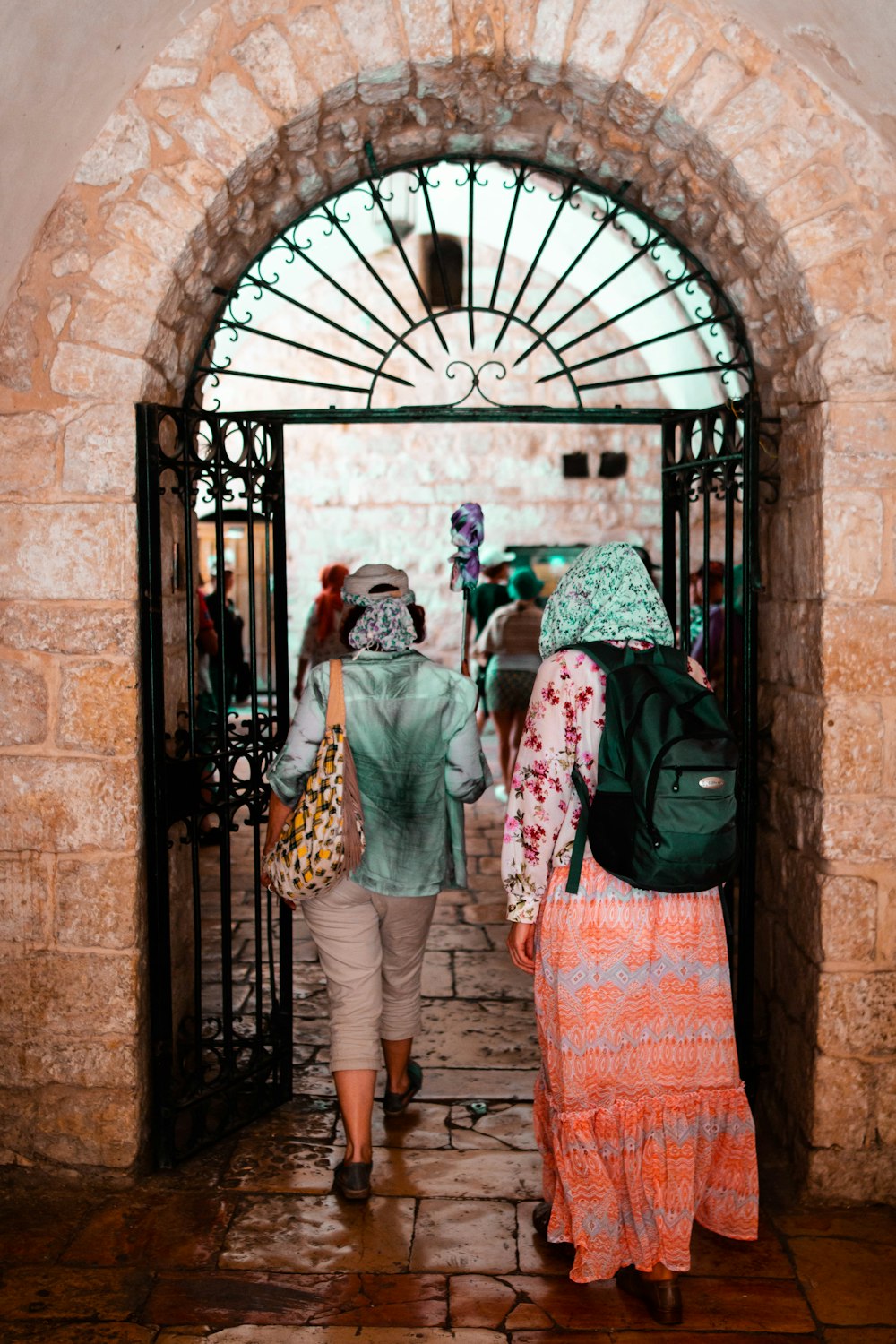 woman in green and white hijab standing beside black metal gate