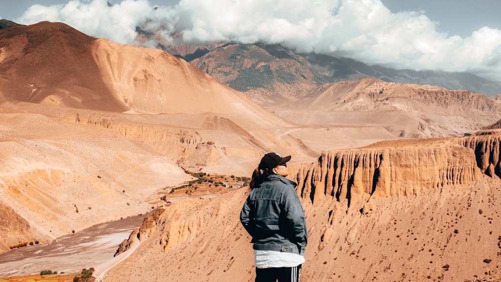 man in black jacket standing on brown rock formation during daytime