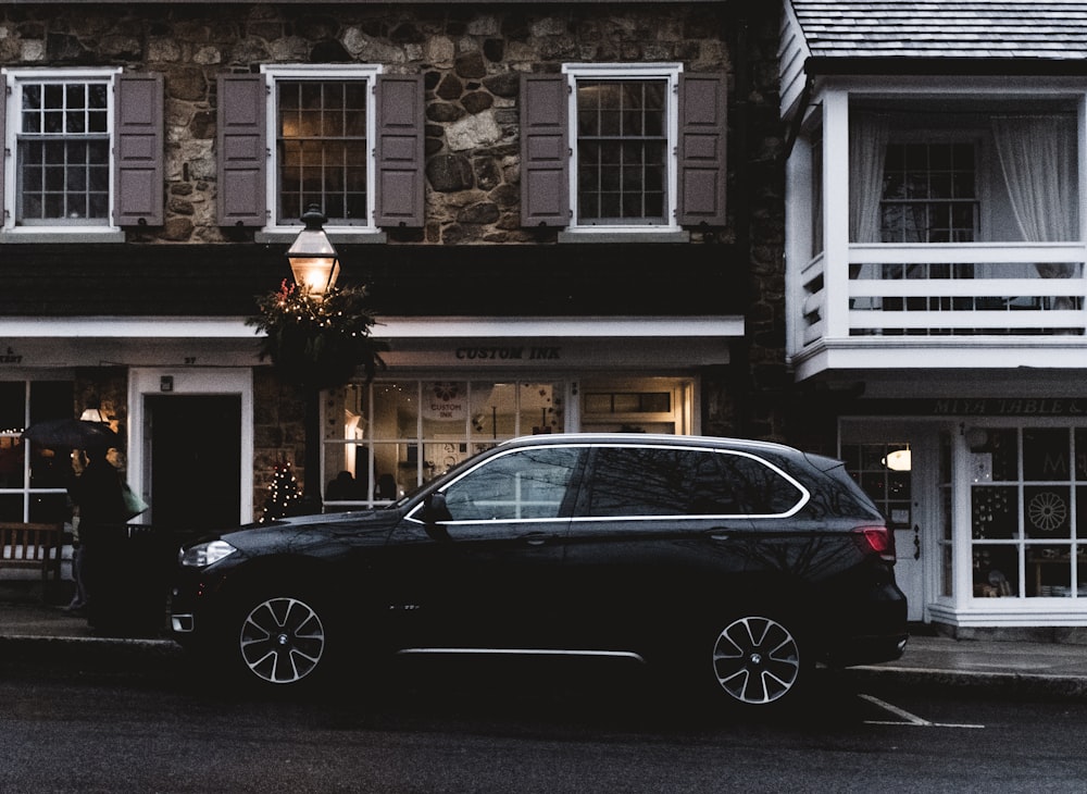 black sedan parked in front of white and brown concrete building during daytime