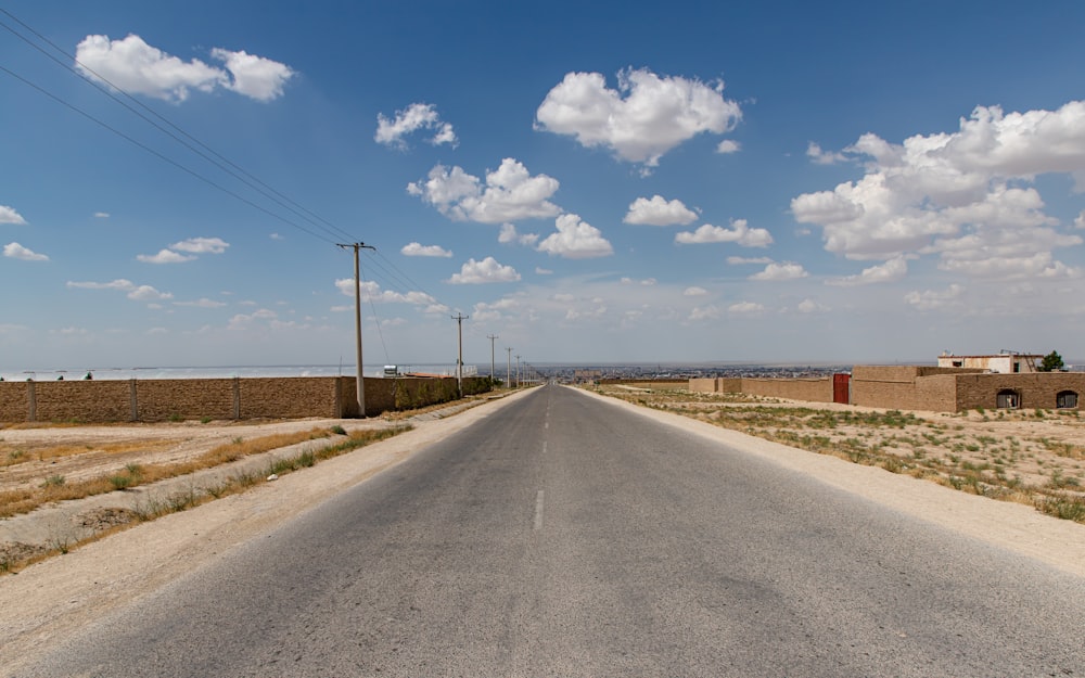 gray concrete road under blue sky and white clouds during daytime