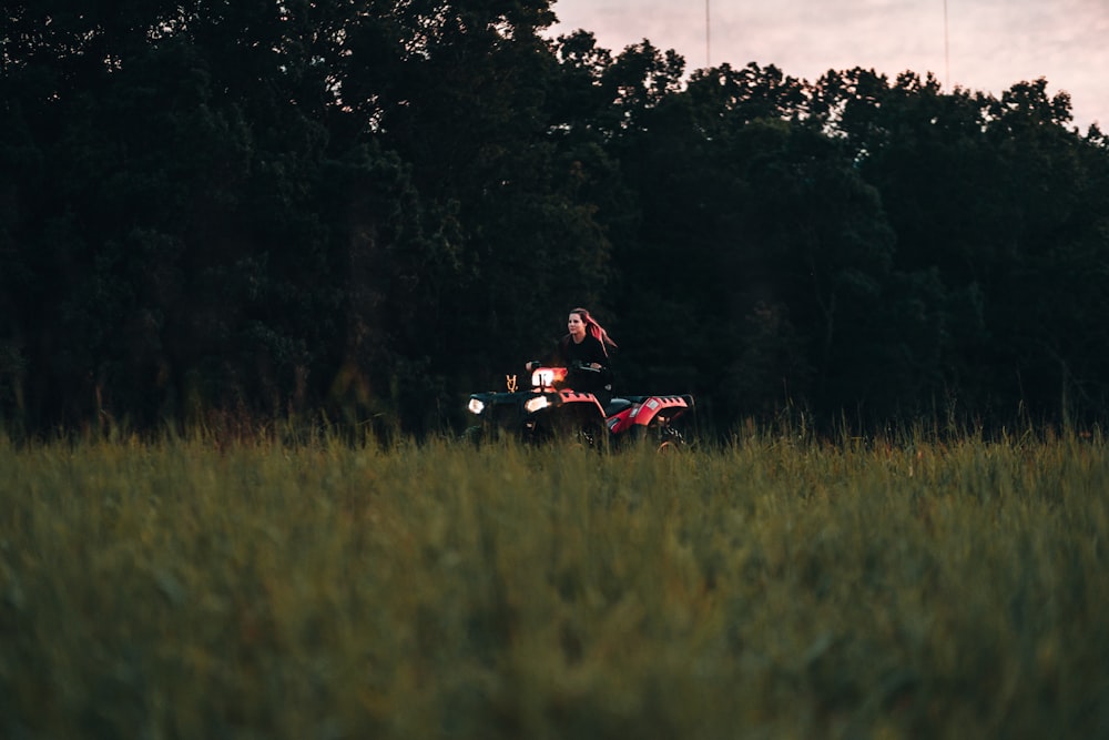 man riding red atv on green grass field during daytime