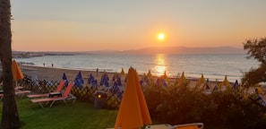 Sunset view over the vibrant beach with colorful umbrellas and people enjoying the warm light