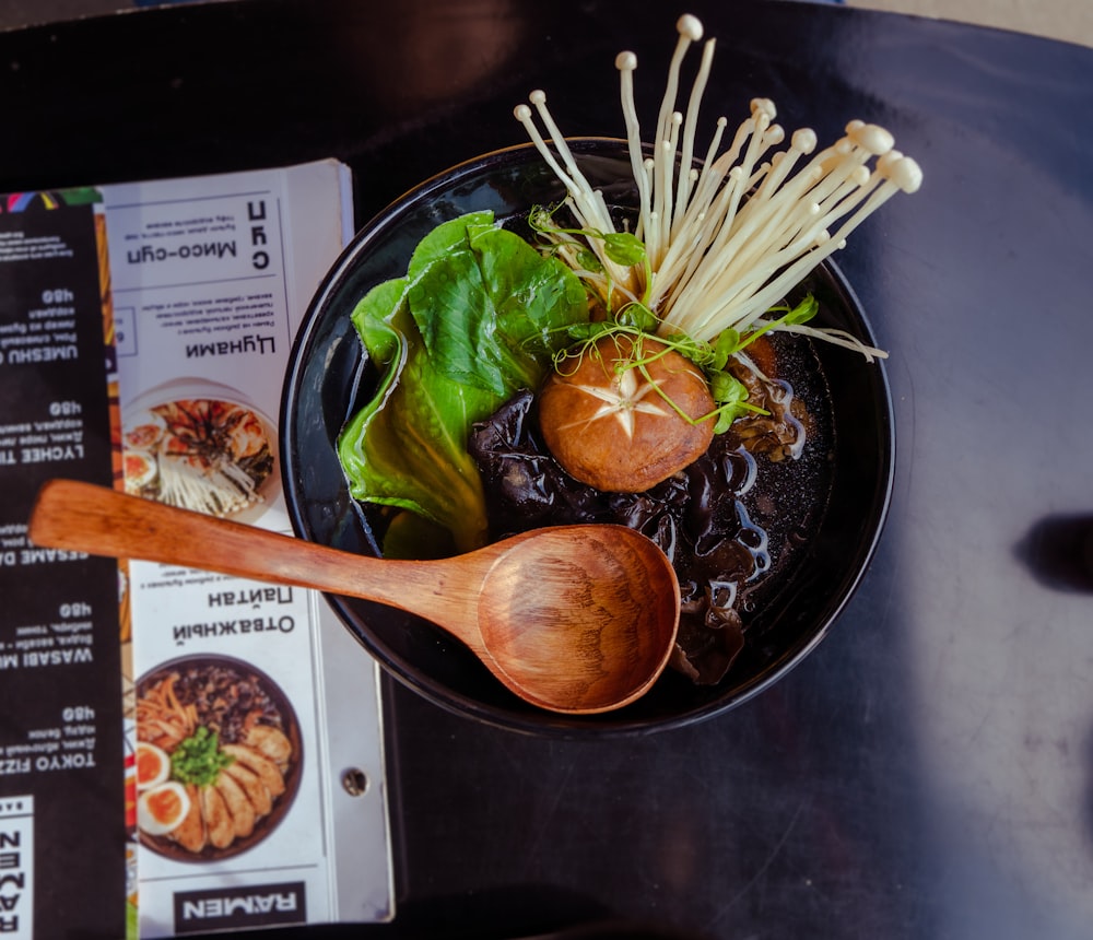 brown wooden spoon on green vegetable in black ceramic bowl