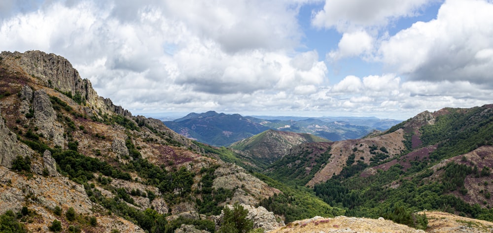 grüne und braune Berge unter weißen Wolken und blauem Himmel tagsüber