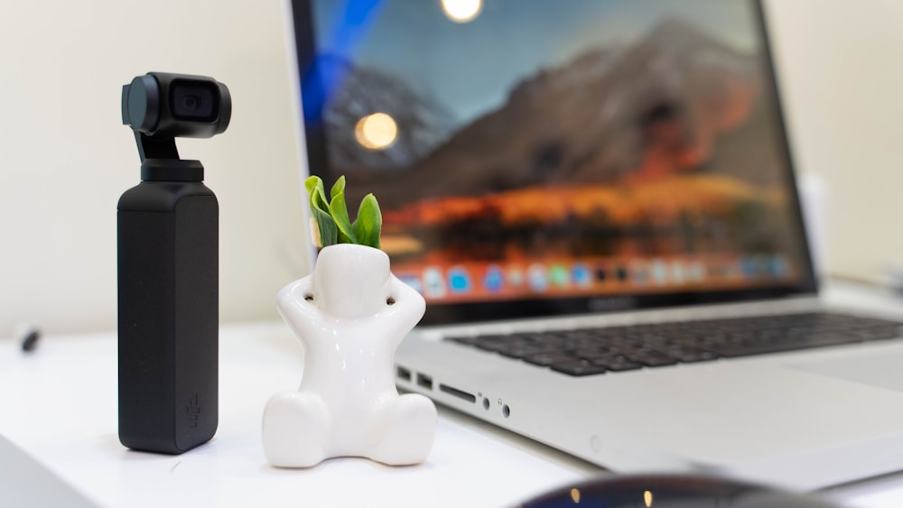 macbook pro beside white ceramic figurine