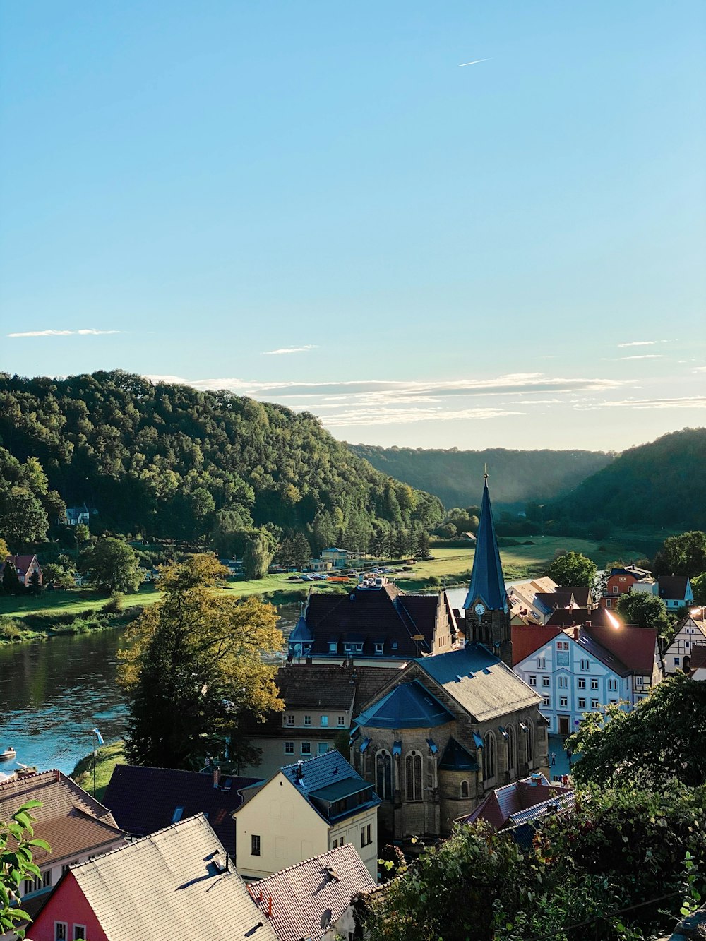 Braunes und weißes Betongebäude in der Nähe von grünen Bäumen und Fluss tagsüber