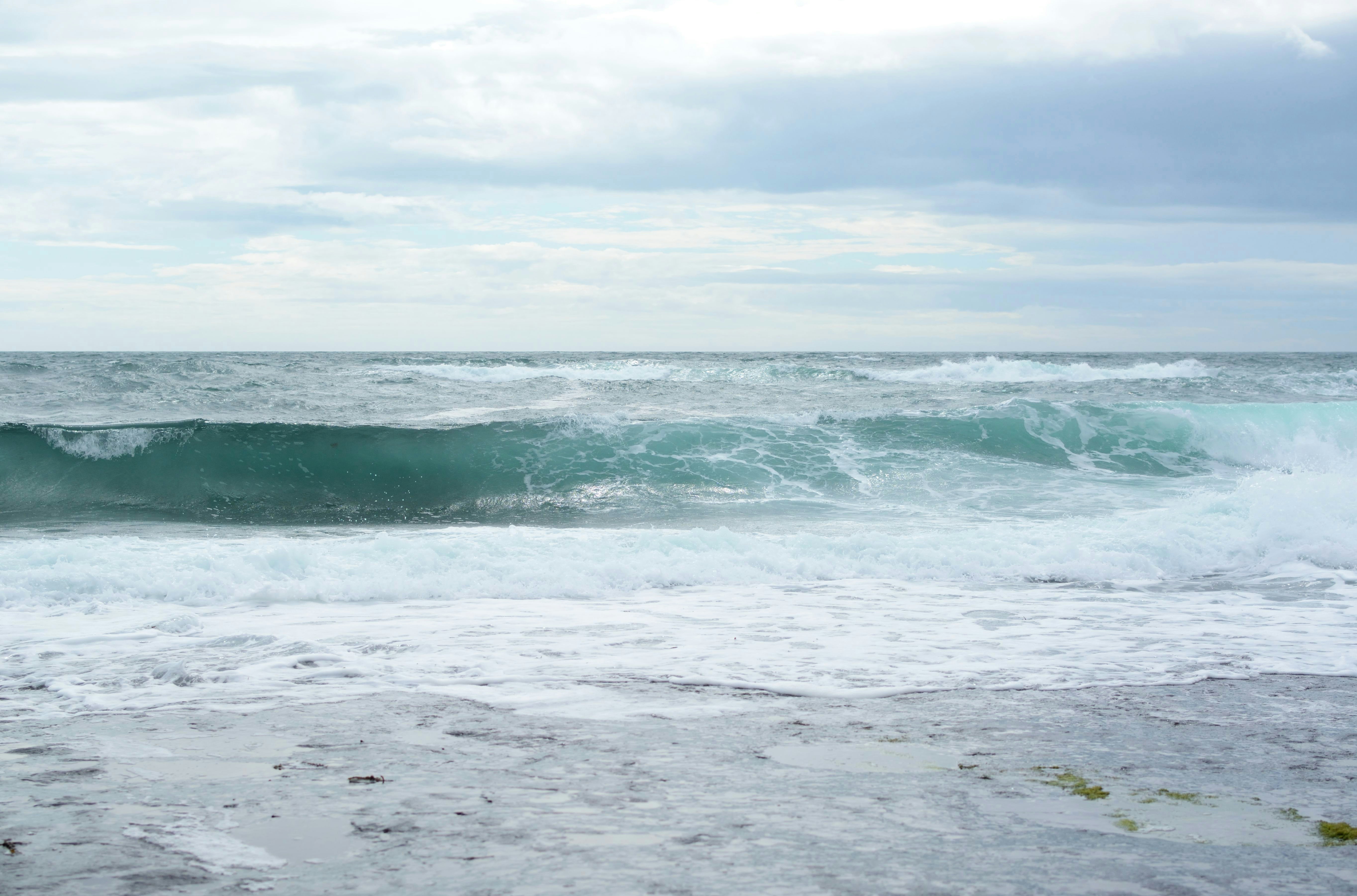 ocean waves under cloudy sky during daytime