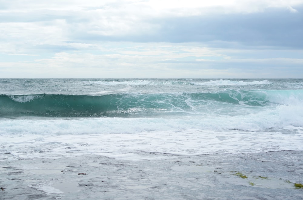 ondas do oceano sob o céu nublado durante o dia