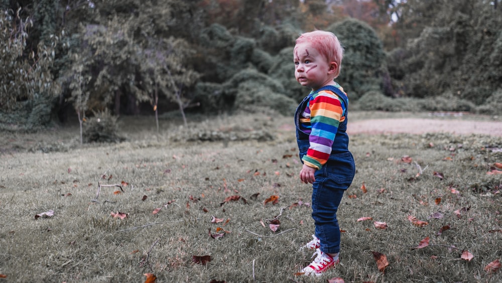 boy in red blue and green plaid dress shirt and blue denim jeans walking on grass