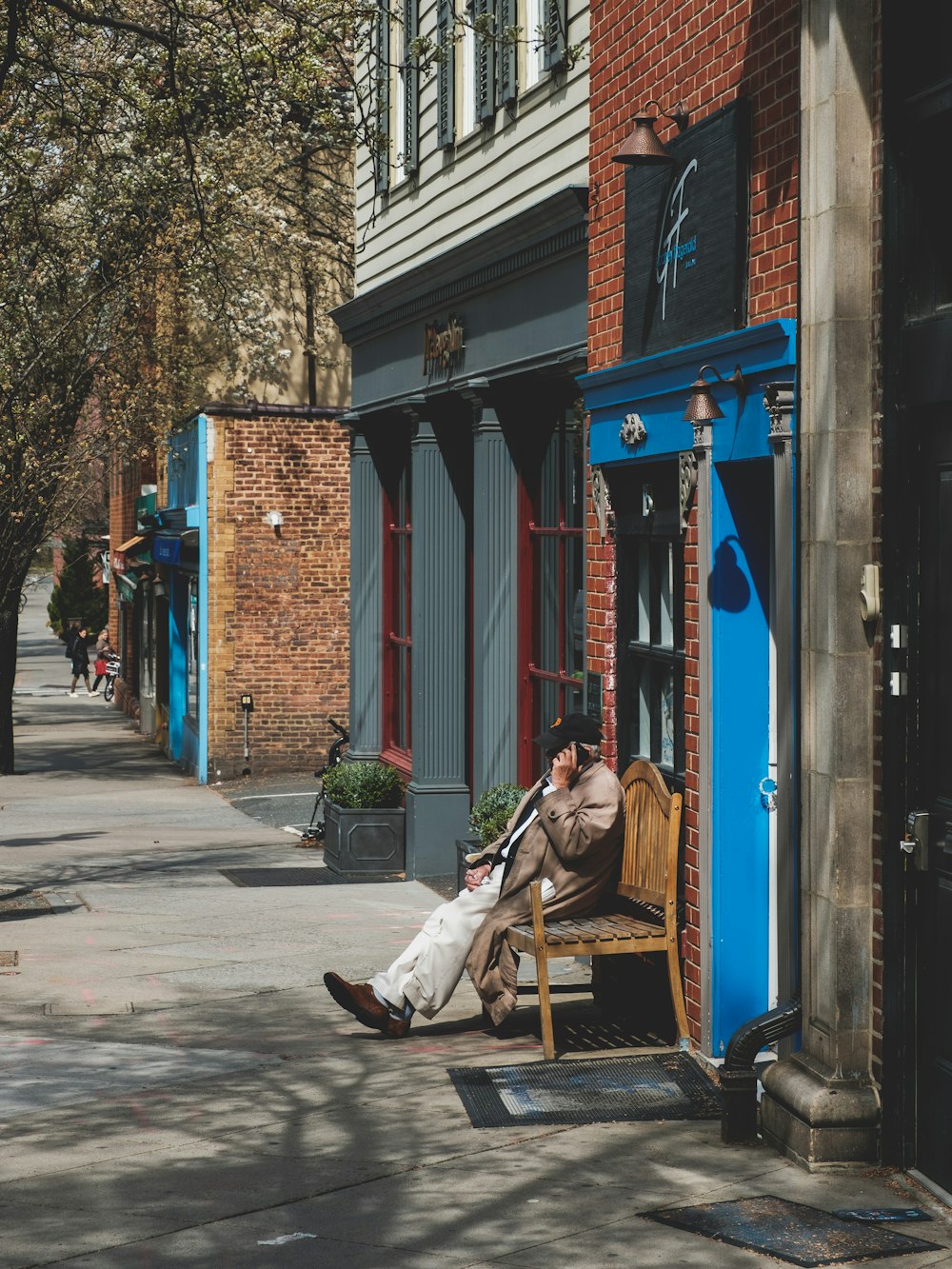 man in white shirt and blue denim jeans sitting on brown wooden bench near blue and